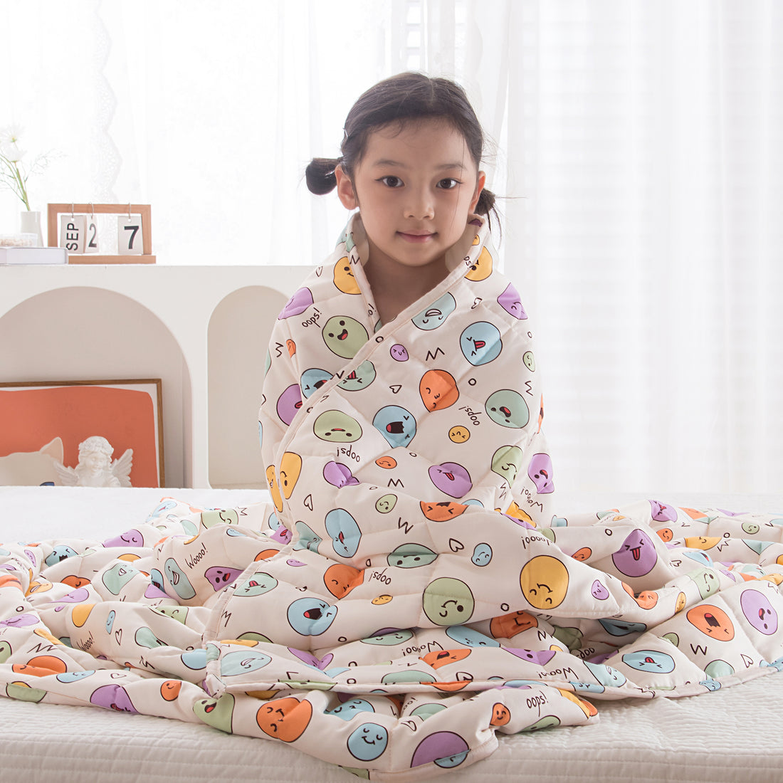 Child on bed with beige emoji weighted blanket