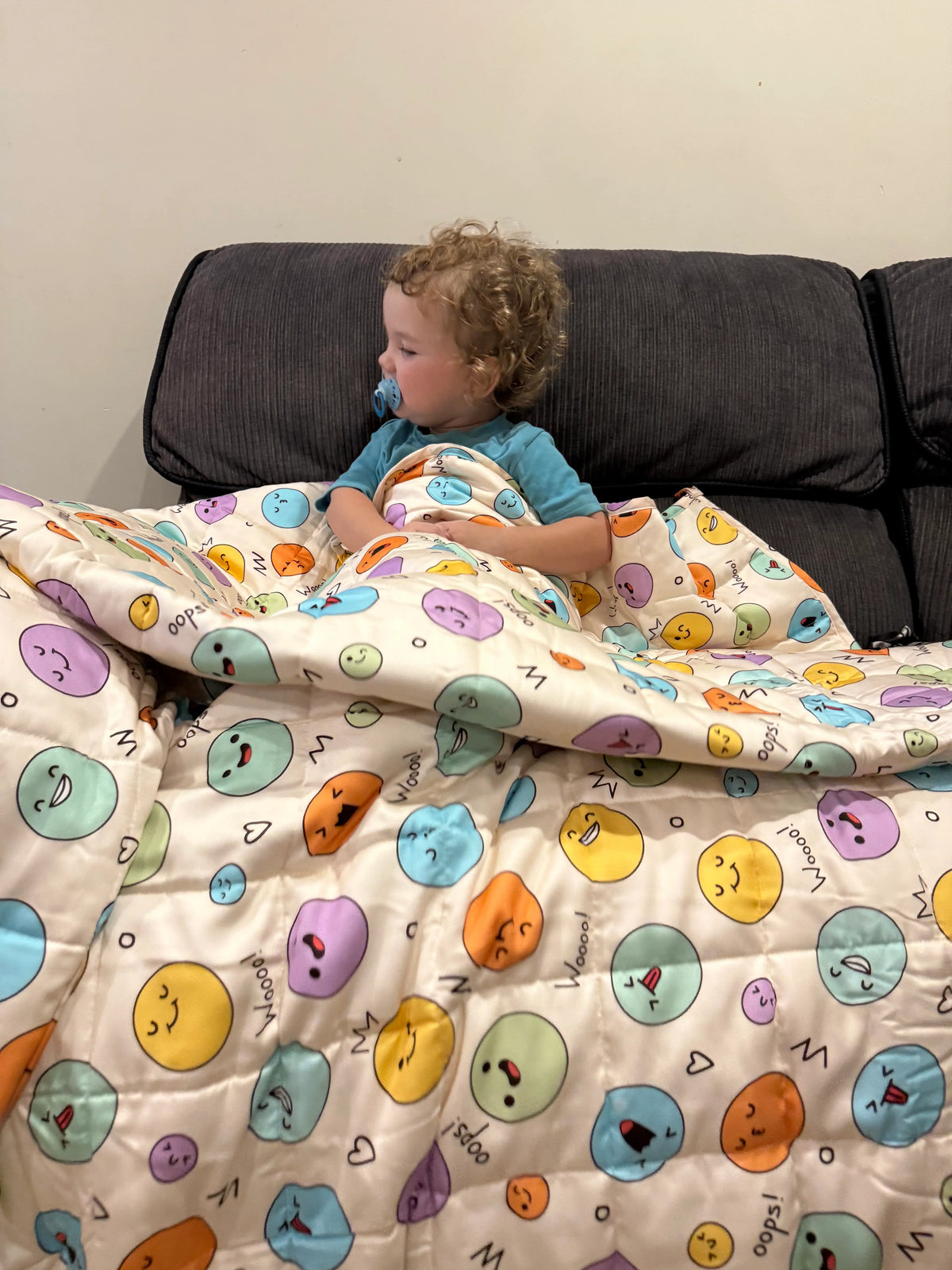 Child lying under a emoji weighted blanket