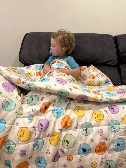 Child lying under a emoji weighted blanket